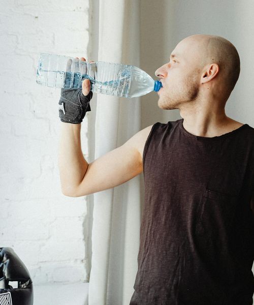 Man performing a controlled strength exercise in a dark gym.